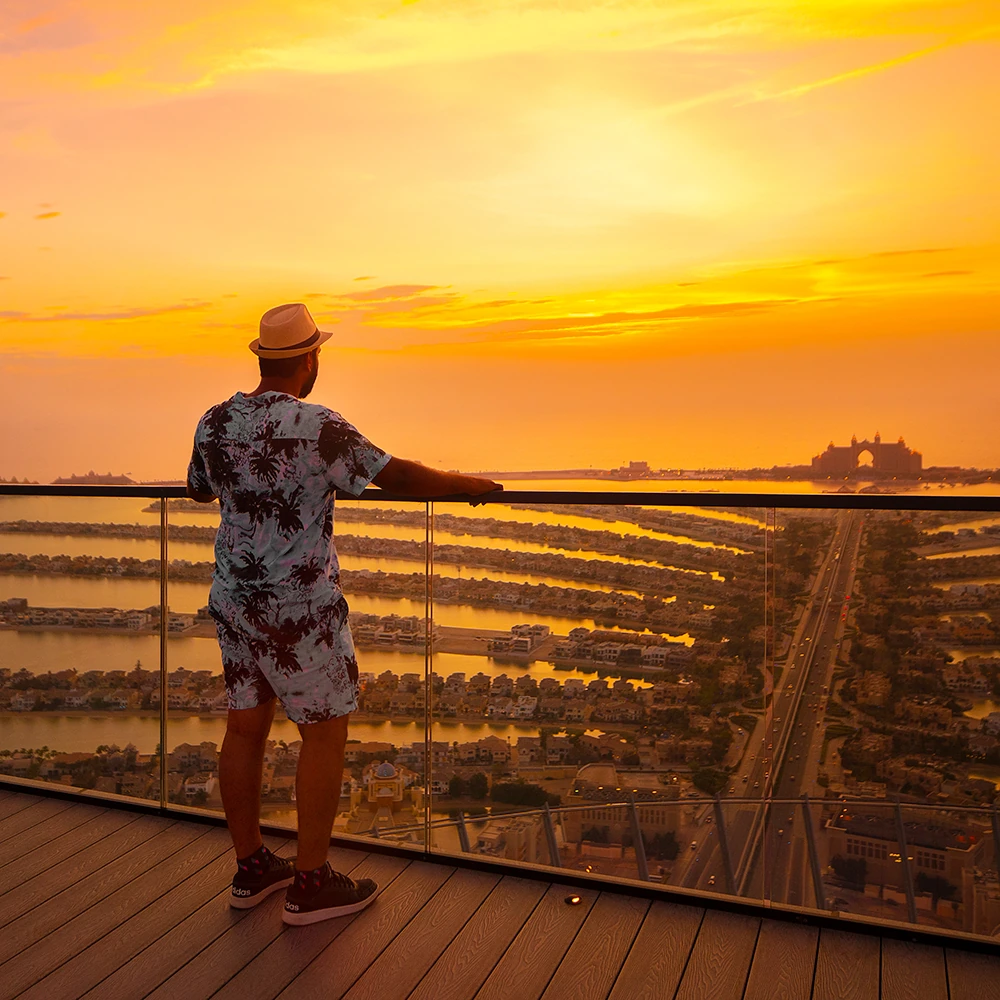 Visitor on The View at The Palm observation deck overlooking Palm Jumeirah at sunset